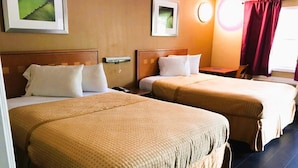 Una habitación de hotel con dos camas, una mesita de noche, una lámpara y un ventanal con cortinas.