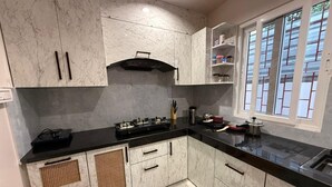 Una cocina con armarios de mármol, encimera negra y una ventana con persianas.