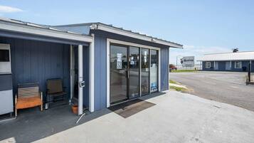 A building with a blue exterior, a glass door entrance, a bench outside, and a parking lot in the background.