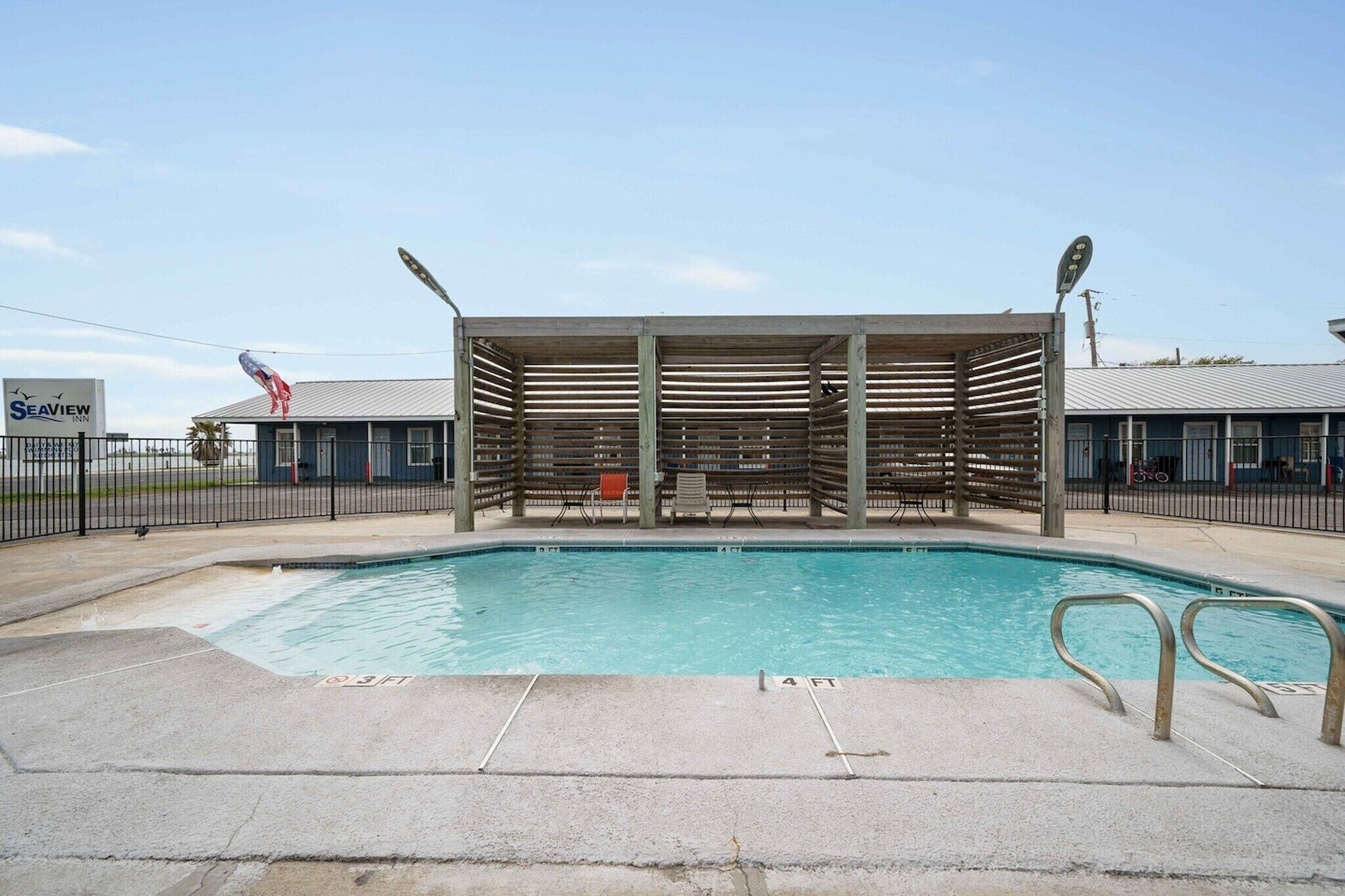 A swimming pool with a wooden deck area, a covered seating area, and a sign for 'Seaview.'