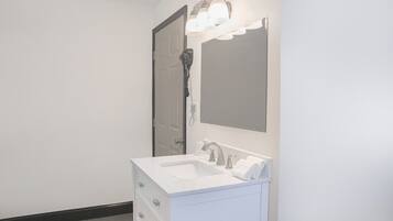 Un baño con tocador blanco, un espejo, un secador de pelo y una lámpara.