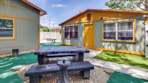 A small, two-story building with a picnic table in the center, surrounded by a green lawn. - Guest House Near Amphitheatre & Hard Rock Casino! (Tampa)