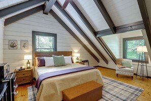 Ein Schlafzimmer mit einem Bett, Nachttischen, einer Bank, einer Lampe und einem Fenster.