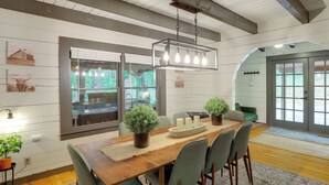 A dining area with a wooden table, chairs, potted plants, and a hanging light fixture. - Marion Cabin w/ Wrap-Around Deck & Outdoor Kitchen (Marion)