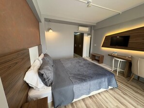 Un dormitorio moderno con cama, mesita de noche y televisor montado en la pared.