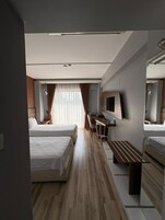 Quarto de hotel com duas camas, uma mesa, um espelho e uma janela com cortinas.