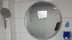 A bathroom with a white sink, a round mirror with a decorative frame, a handheld mirror, a towel rack, and a soap dispenser. - Yalim Garden Park Otel (Sivasli)