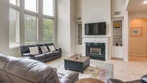 Ein Wohnzimmer mit Kamin, einer Couch, einem Couchtisch und einem Fernseher.