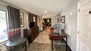 A hotel room with a dining area, a TV, a fireplace, and a view of the outdoors. - King Bed Non-Smoking (Ridgeway, SC)