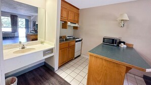 A compact kitchen with a sink, stove, microwave, and cabinets. - King Bed Non-Smoking (Ridgeway, SC)
