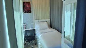 A bedroom with a bed, a desk, a chair, a wardrobe, and a ceiling light fixture.