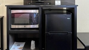 Uma cozinha compacta com micro-ondas, geladeira e uma TV de tela plana em um armário preto.