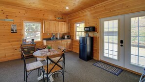 L’intérieur d’un chalet en bois comprend une cuisine, un coin repas et une porte donnant sur l’extérieur.