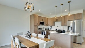 Una cocina moderna con armarios de madera, electrodomésticos de acero inoxidable e iluminación colgante.