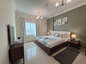 A bedroom with a bed, bedside tables, a mirror, a window with curtains, and a city view. - Luxury 3BR  Sea & Skyline View  Noor Mosque view (Sharjah)