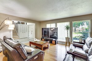 A living room with leather sofas, a flat-screen TV, a wooden coffee table, and a staircase leading to a closet. - Kansas City Extended Stay Near Stadiums & Downtown (Kansas City)