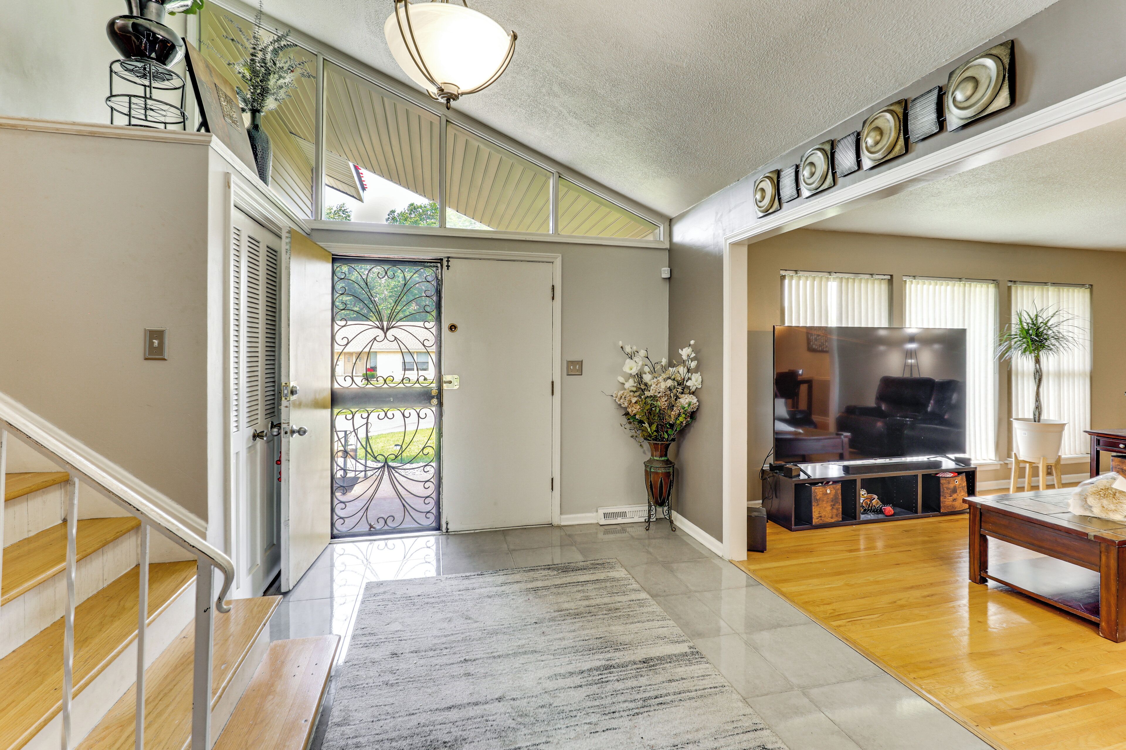 A spacious living area with a fireplace, a dining table, and a staircase leading to an upper level.