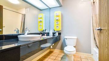 A bathroom with a sink, mirror, toilet, and towel racks.