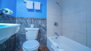 A bathroom with a toilet, sink, bathtub, and blue walls. - Queen Bed | Non smoking (Corpus Christi TX)