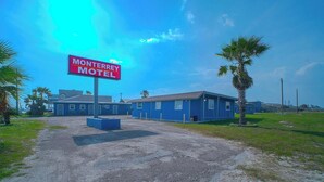 A motel with a prominent sign, a parking lot, and a building with a flat roof. - Queen Bed | Non smoking (Corpus Christi TX)
