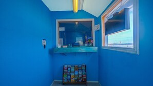 A room with blue walls, a window, a shelf with items, and a bulletin board. - Queen Bed | Non smoking (Corpus Christi TX)