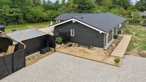 Ett modernt hus med en mörk fasad, ett sluttande tak och en träaltan.