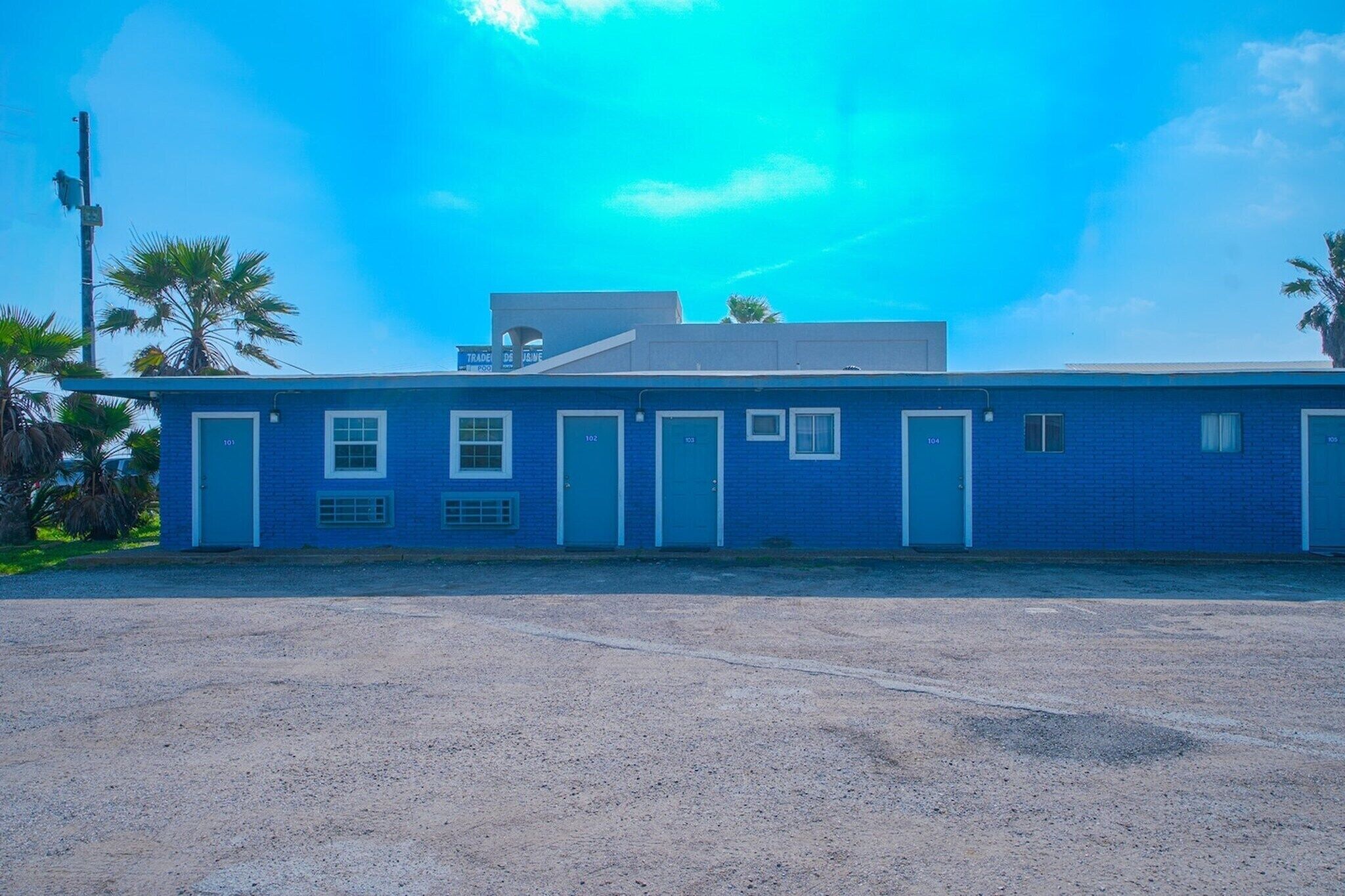 Un bâtiment bleu avec des portes numérotées, un toit plat et un ciel dégagé.