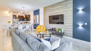 A modern living room with a sofa, coffee table, and a yellow armchair. - 9 Mi to Disney ChampionsGate Condo Plus Water Park (Davenport)