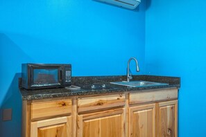 A kitchen with a microwave, sink, and wooden cabinets. - Corpus Christi Tx | Queen Bed (Corpus Christi TX)