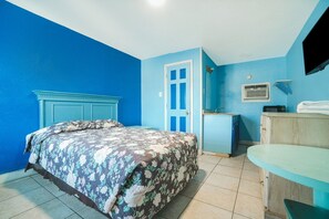 A room with a bed, a desk, a chair, a TV, and a door. - Corpus Christi Tx | Queen Bed (Corpus Christi TX)