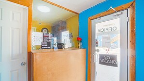 A reception desk with a 'NO VACANCY' sign, a 'SODA' sign, and an 'OFFICE' sign.