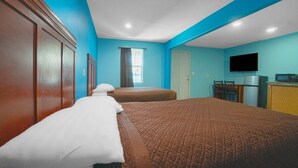 A hotel room with two beds, a television, a desk, and a window.