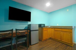 A kitchen with a refrigerator, microwave, wooden cabinets, and a flat-screen TV mounted on the wall. - 2 Full Beds with  Kitchenette (Corpus Christi TX)