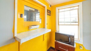 A room with yellow walls, a window, a microwave, and a sign indicating free WiFi.