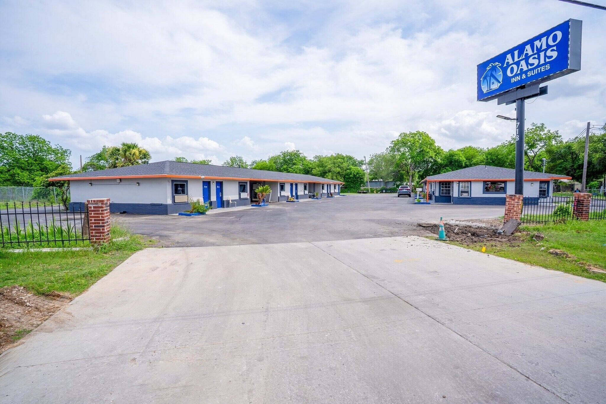 Ett motell med en skylt som visar texten ”Alamo Oasis Inn & Suites”. Byggnaden är enkel i sin utformning och har en parkeringsplats framför.