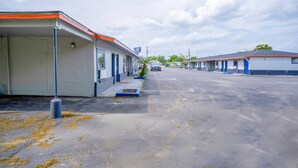 A motel with a covered parking area, a single-story structure, and a clear sky.