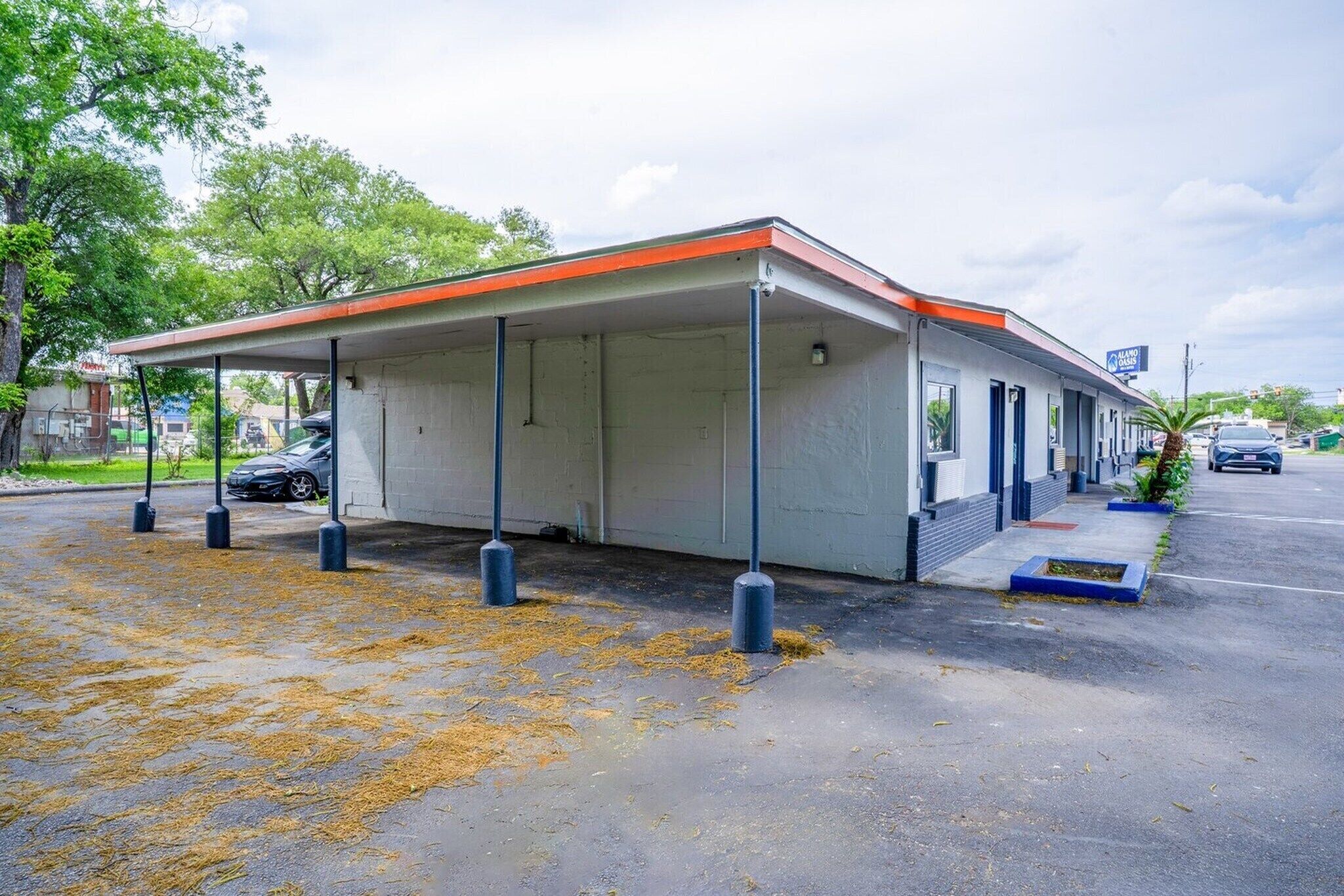 A covered outdoor area with a building, bollards, and a parking lot.