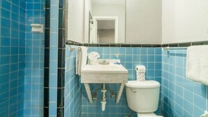A bathroom with blue tiles, a white sink, a toilet, and a mirror.