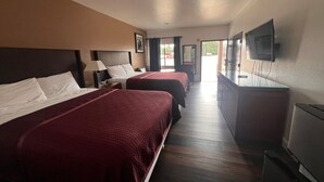 A hotel room with two beds, a TV, and a desk.