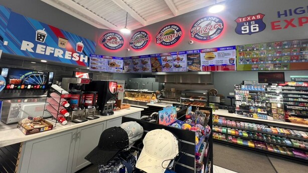 A fast-food restaurant with a Texas-themed decor, including signs for burgers, chicken, and pizza, and a menu board displaying various food items.