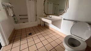 A bathroom with a bathtub, a sink, a toilet, and a large mirror.