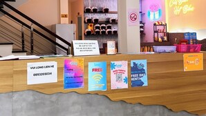 Una recepción con un cartel que indica un número de contacto, una escalera y un letrero de neón al fondo.