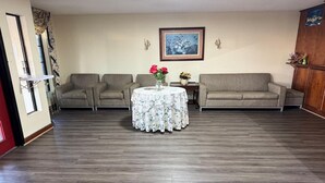 A living room with two sofas, a round table with a floral tablecloth, and a framed picture on the wall.