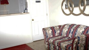 A room with a white door, a floral sofa, and a wall with three circular mirrors. - King Bed with Kitchenette Non-Smoking (Marshall, MO)