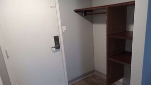 A room with a white door, a wooden shelf unit, and a light switch on the wall. - King Bed with Kitchenette Non-Smoking (Marshall, MO)