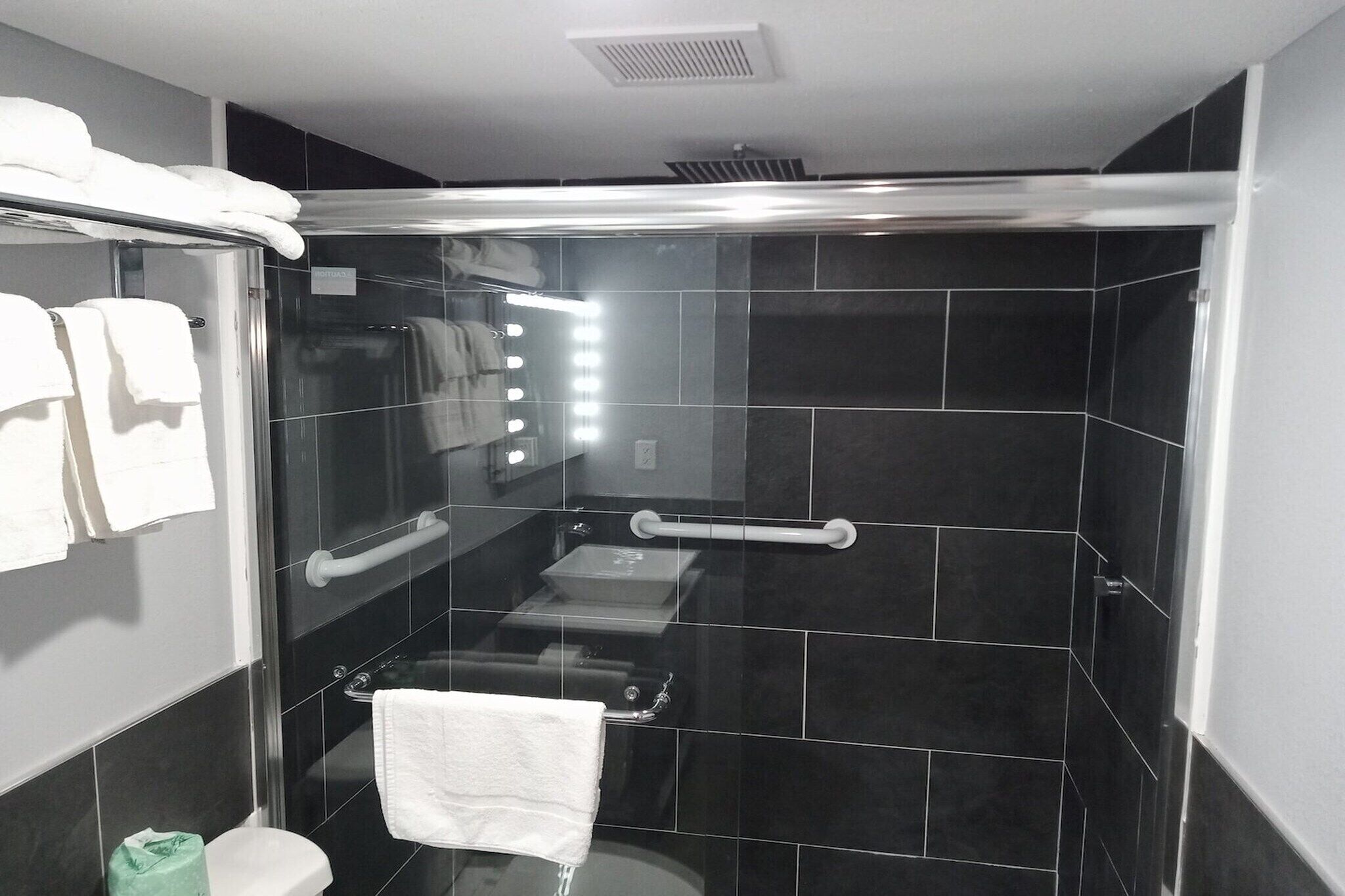 Ein modernes Badezimmer mit einer gläsernen Duschkabine, Toilette, Waschbecken und einem Handtuchhalter mit Handtüchern.