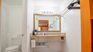 Un baño con inodoro blanco, lavamanos con espejo y toallero.