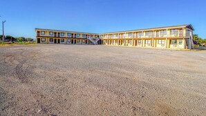 Un motel con un patio central, varios balcones y una escalera que conduce a los pisos superiores.