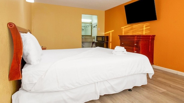 Una habitación de hotel con una cama, un televisor montado en la pared y un aparador de madera.
