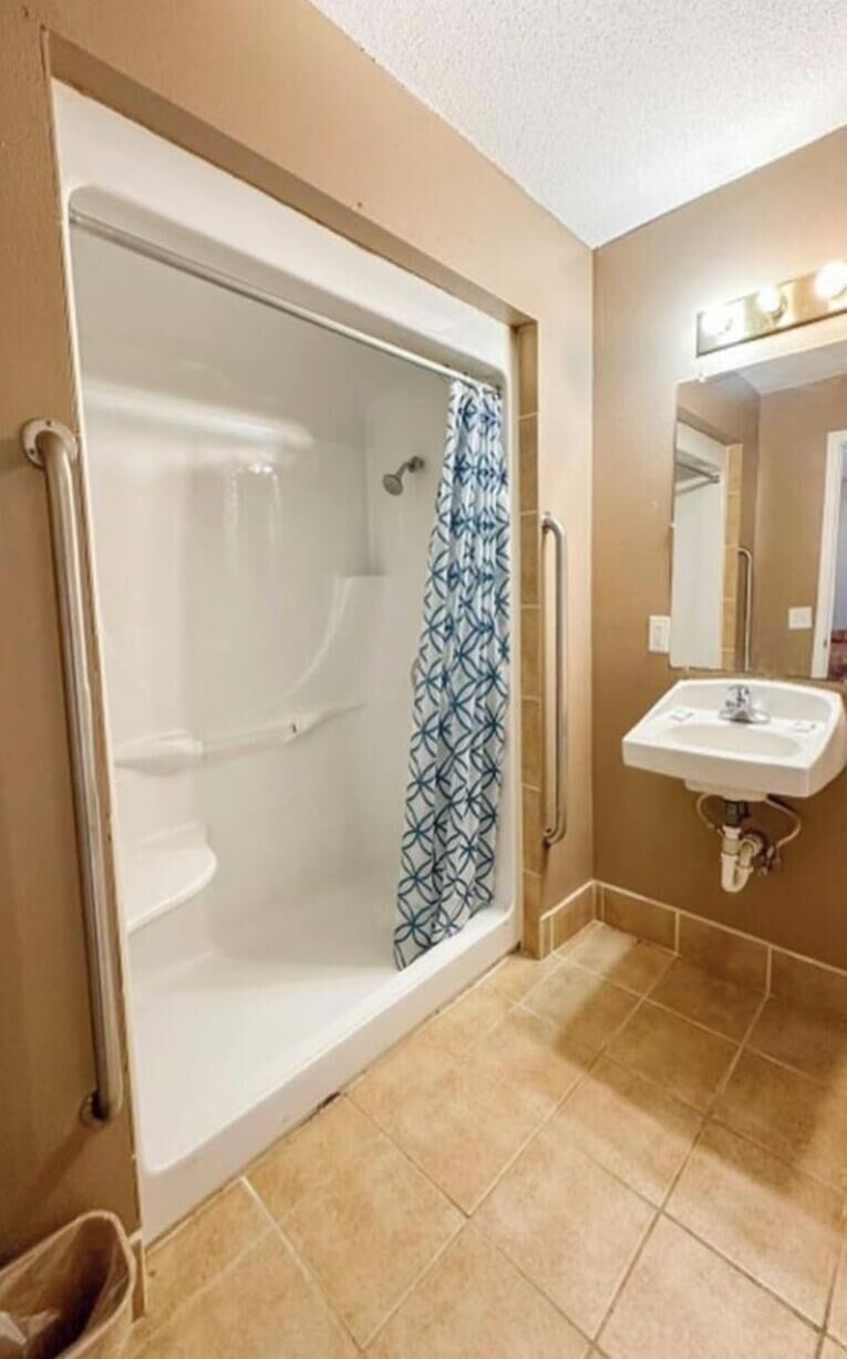 Un baño con ducha a nivel del suelo, lavamanos y espejo con iluminación.